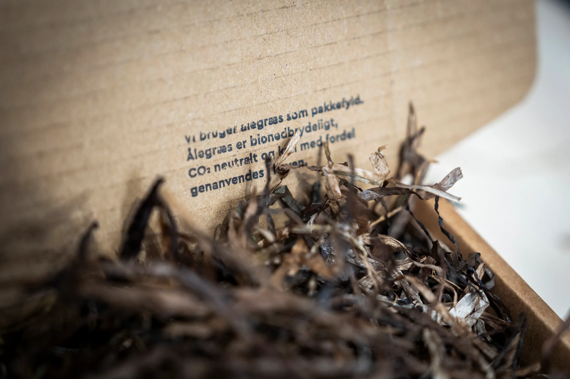 Nærbillede af brun dansk ålegræs brugt som CO₂-neutral, genanvendelig emballagefyld i en åben papæske